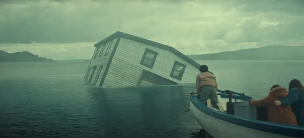 "A partially submerged house tilts in a misty lake as three people in a small boat observe, with cloudy skies and distant hills creating a dramatic, mysterious atmosphere."